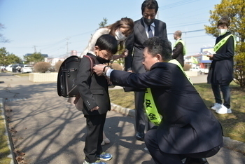 ずーしーほっきーのキーホルダーを新入学児童につける池田市長